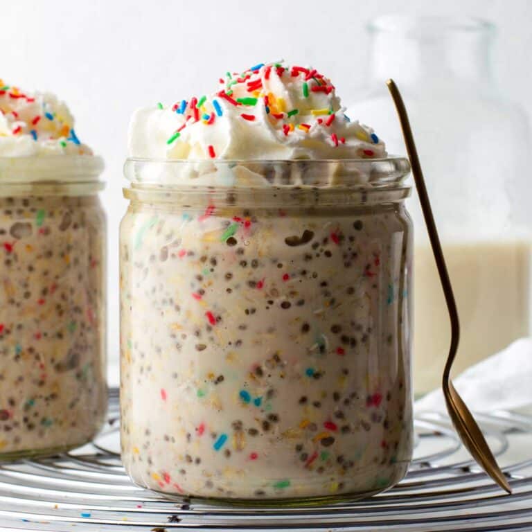 Birthday cake overnight oats in a jar, topped with whipped cream and sprinkles.