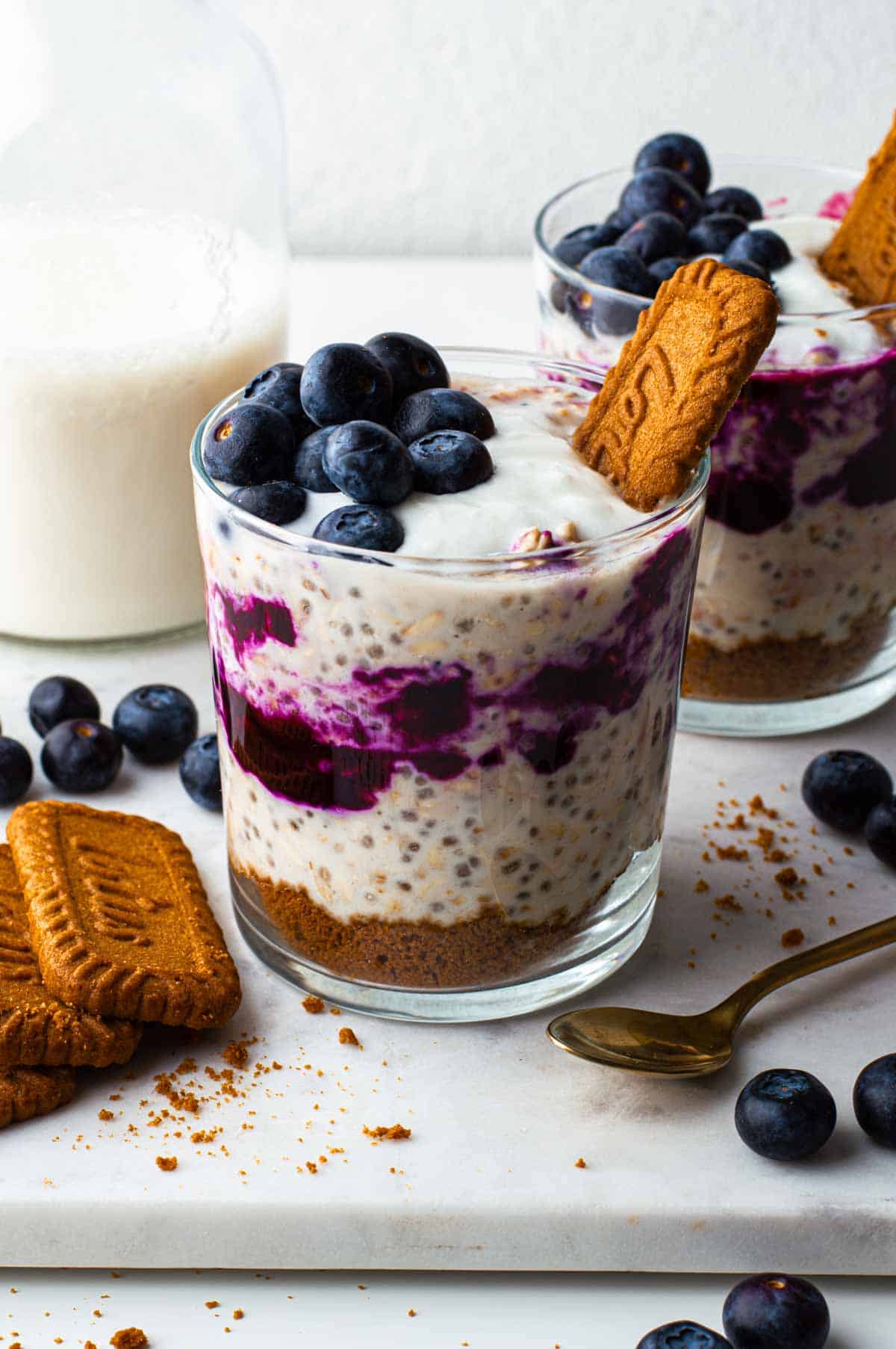 Overnight oat blueberry cheesecake in a glass with fresh blueberries on top.