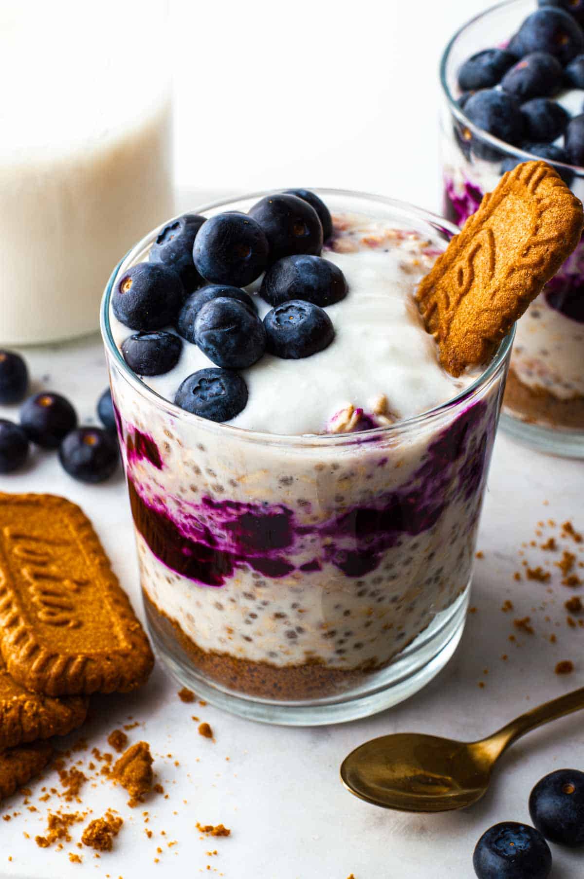Overnight oat blueberry cheesecake in a glass with fresh blueberries on top.