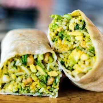 A burrito stuffed with a chickpea avocado mixture and sliced in half to show the inside.