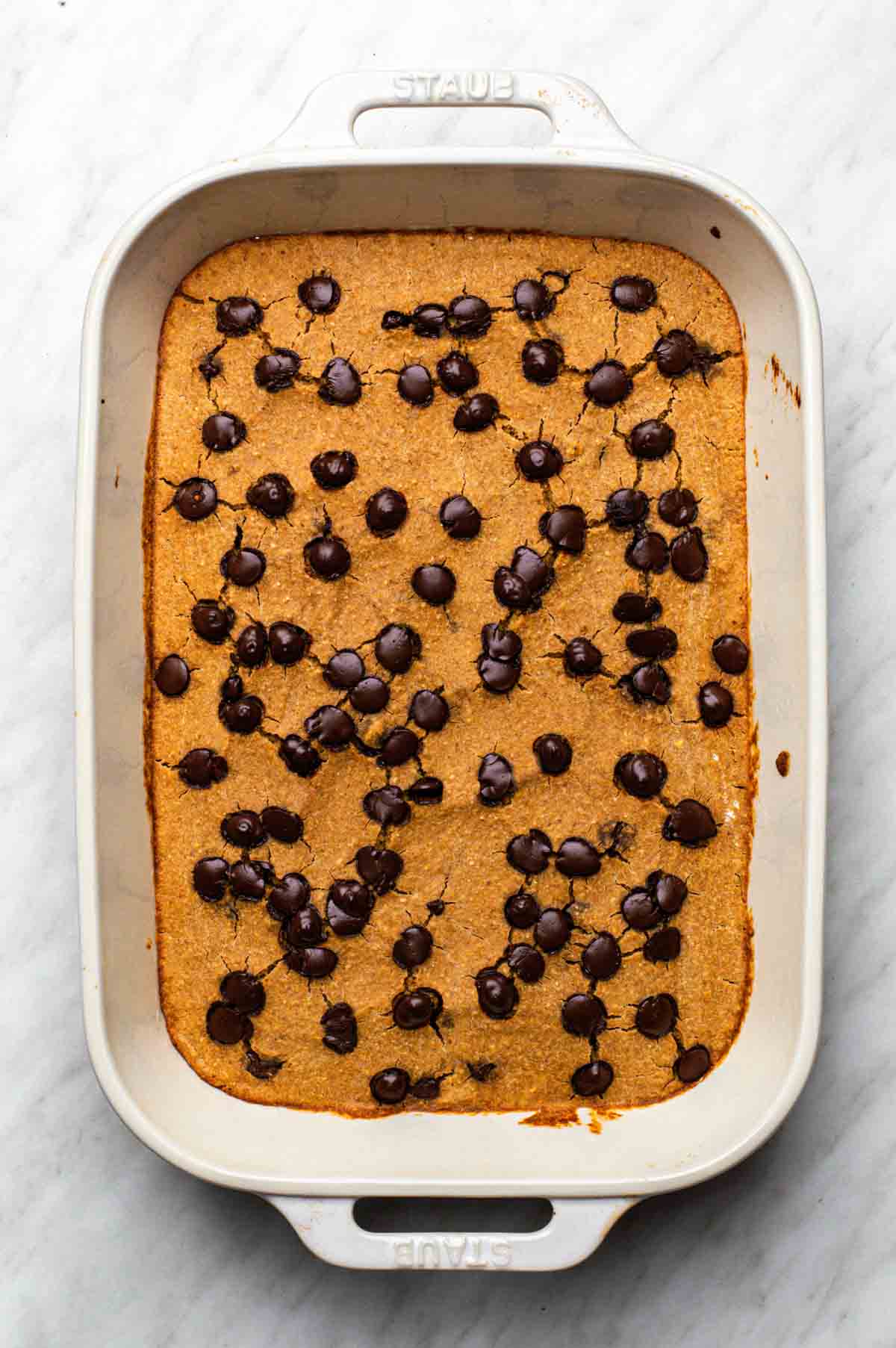 Baked oats made without banana in a baking dish topped with chocolate chips.