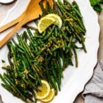 Frozen green beans recipe on a serving platter with lemon slices.
