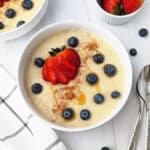 Vegan cream of wheat in a bowl topped with berries, cinnamon, and maple syrup.