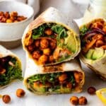 A kale wrap sliced in half and stacked, displaying the crispy chickpeas and kale inside.