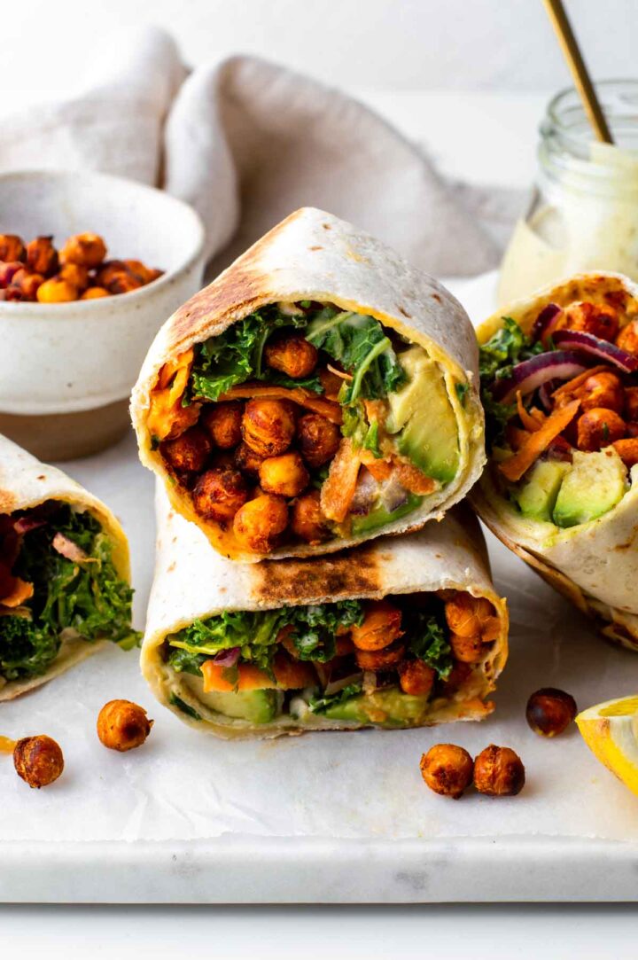 A kale wrap sliced in half and stacked, displaying the crispy chickpeas and kale inside.