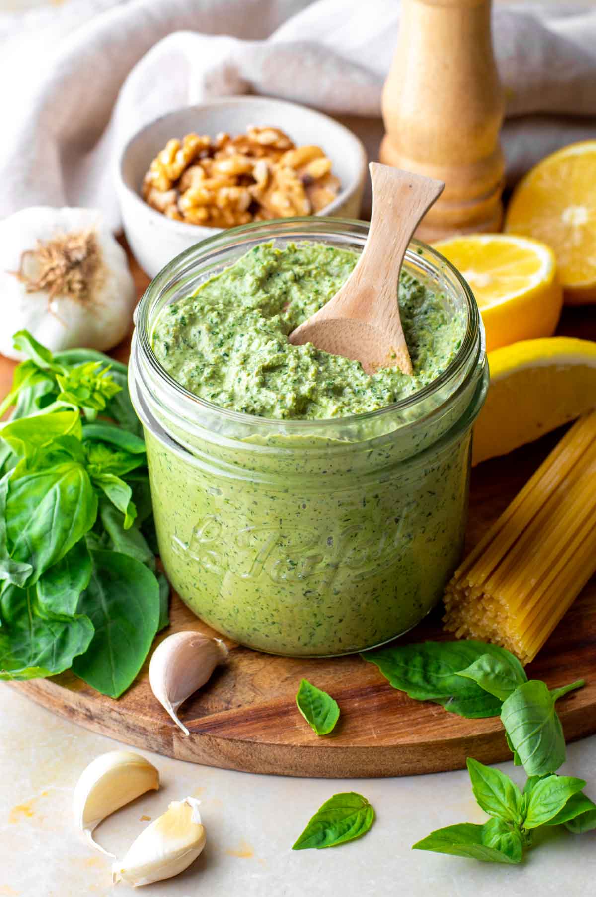 Vegan walnut pesto in a glass jar with a wooden spoon.