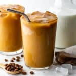 An iced almond milk latte in a tall glass with a metal straw.