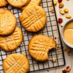 Peanut butter cookies on a cooling rack with a bite taken out of one cookie.