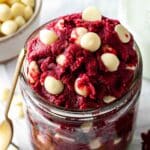 Edible red velvet cookie dough in a glass jar with white chocolate chips.