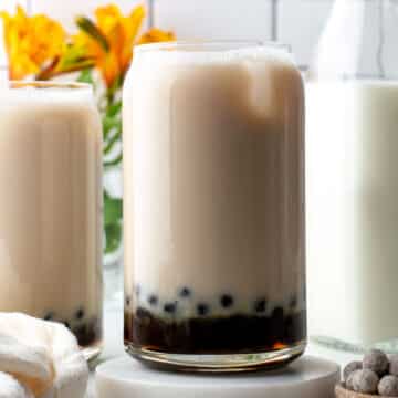 Jasmine milk tea with boba pearls in a tall glass.