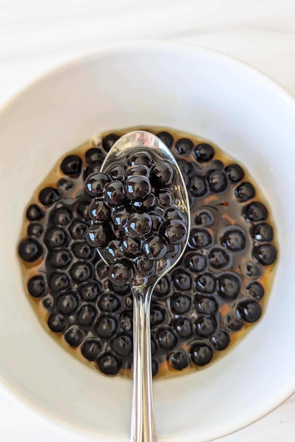 A spoonful of cooked boba pearls mixed with maple syrup.