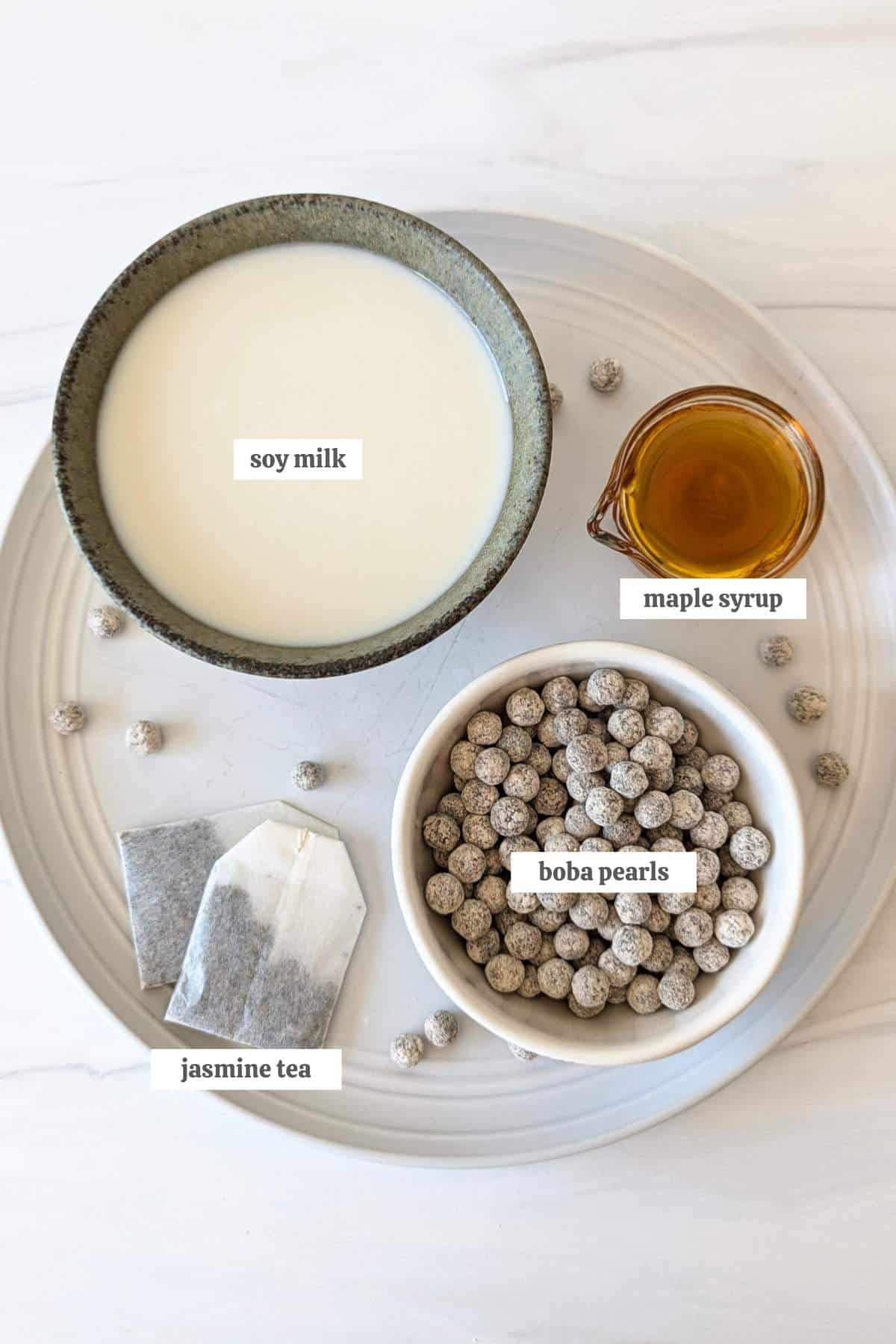 Gathered ingredients for jasmine milk tea measured in individual bowls and labeled.