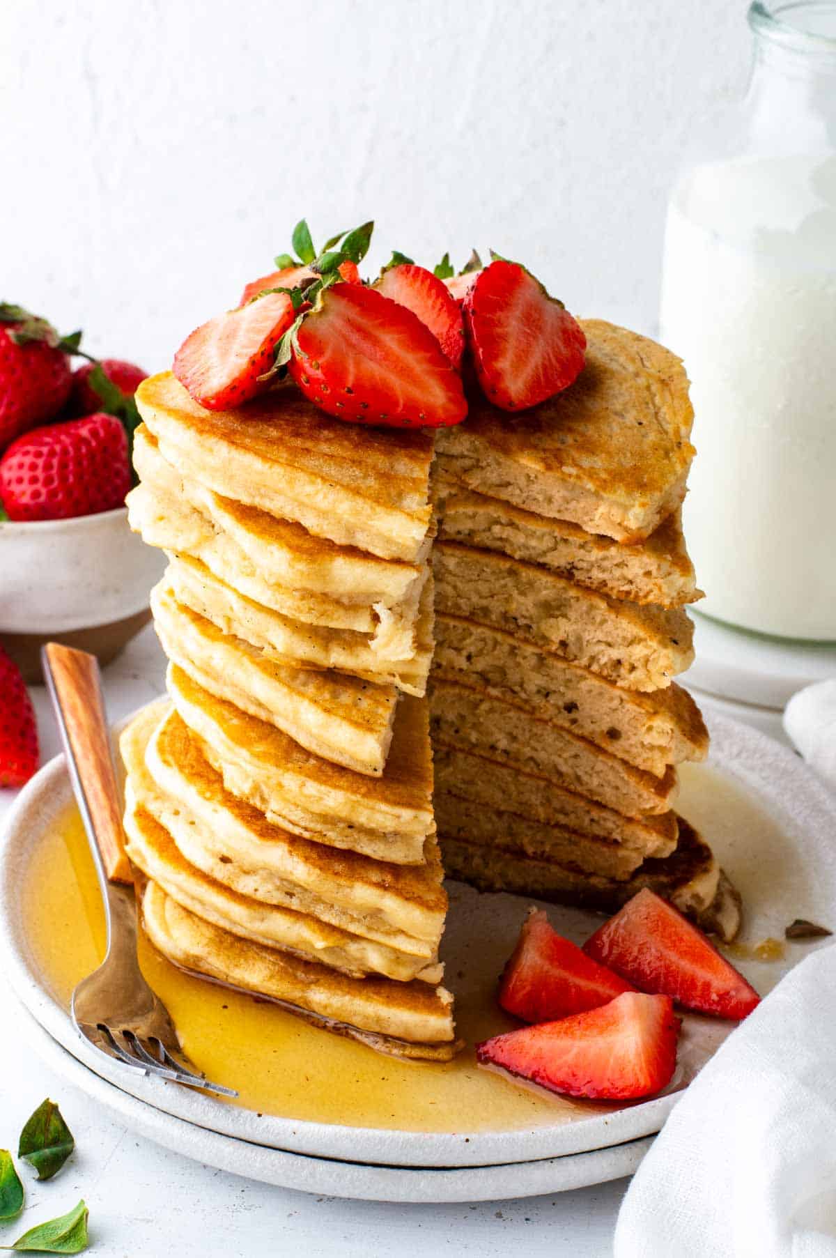 A tall stack of bisquick vegan pancakes with a triangle sliced out to show the fluffy layers of pancakes.