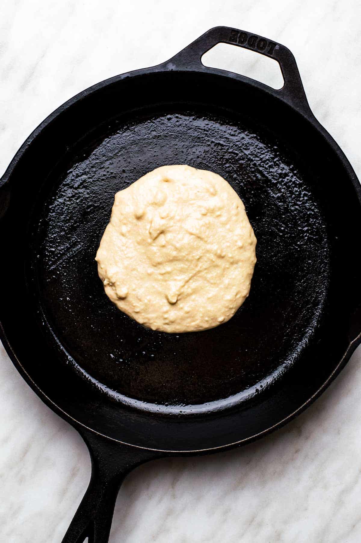 A scoop of vegan bisquick pancake in cooking in a skillet.