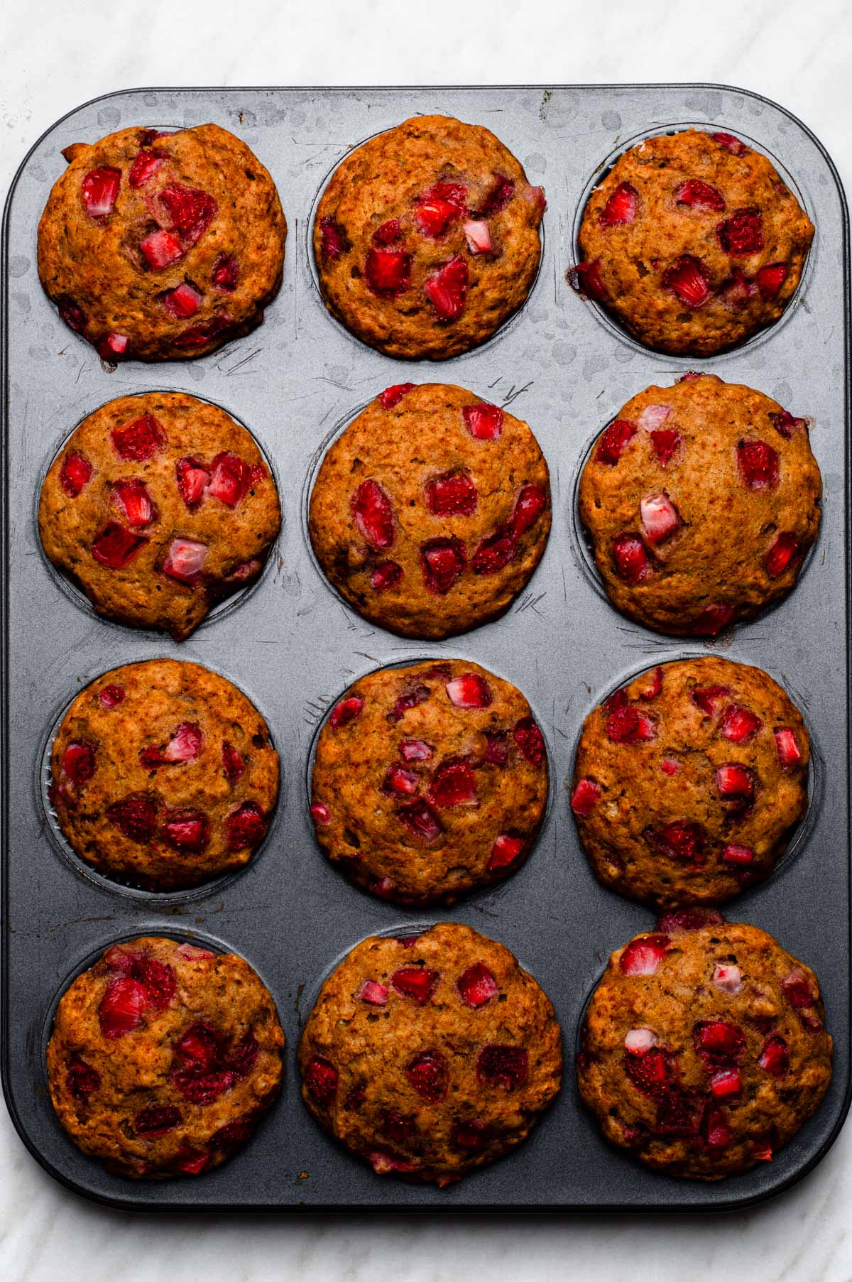 Baked vegan strawberry muffins in a muffin tin pan.