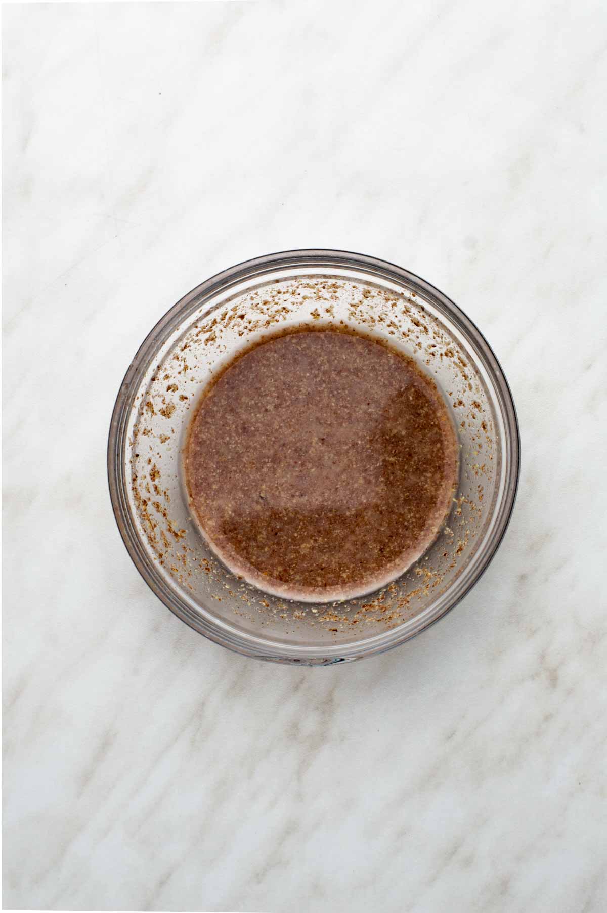 A small clear glass bowl filled with flaxseed mixed with water.