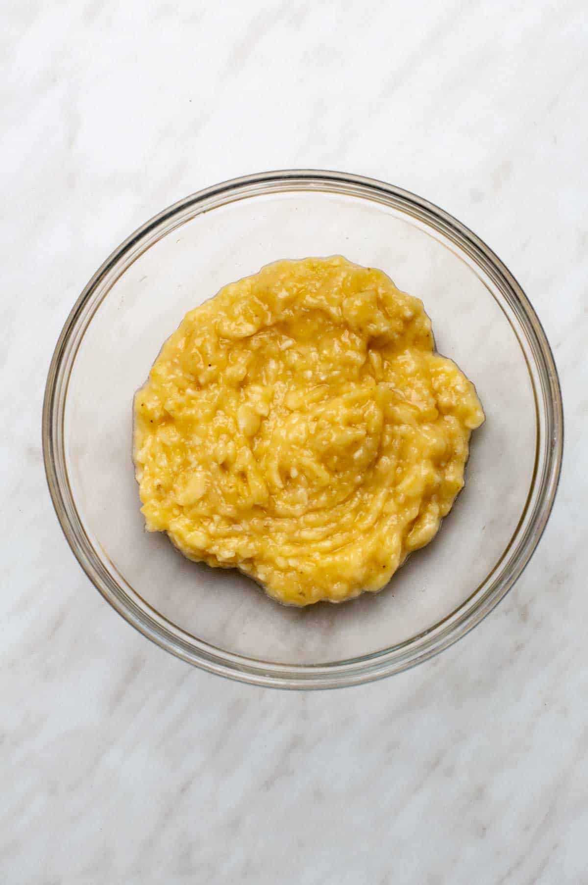 A clear glass bowl of mashed bananas.