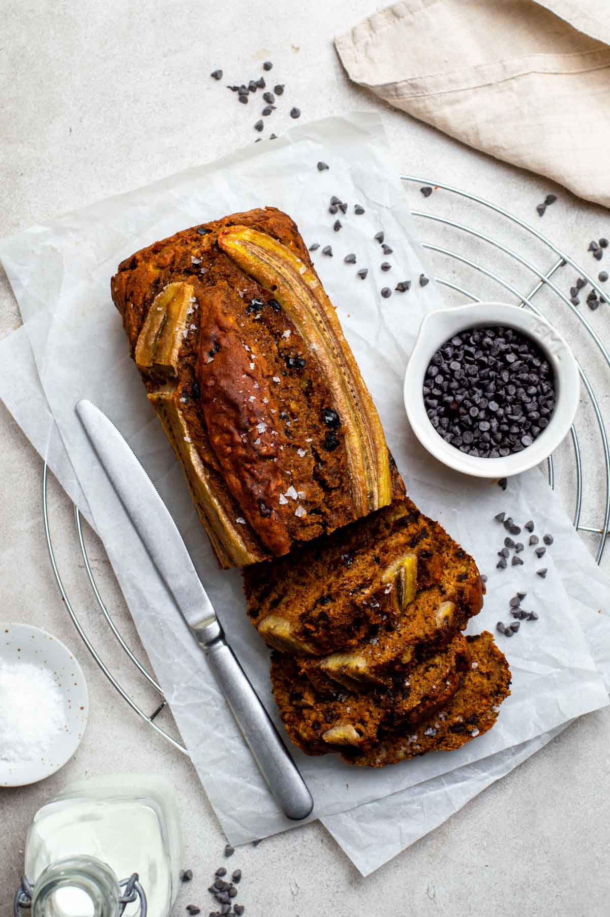 A partially sliced loaf of healthy WFPB banana bread, sprinkled with flaky sea salt.
