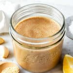Tahini balsamic dressing in a small mason jar placed over a marble board.