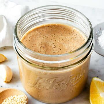 Tahini balsamic dressing in a small mason jar placed over a marble board.
