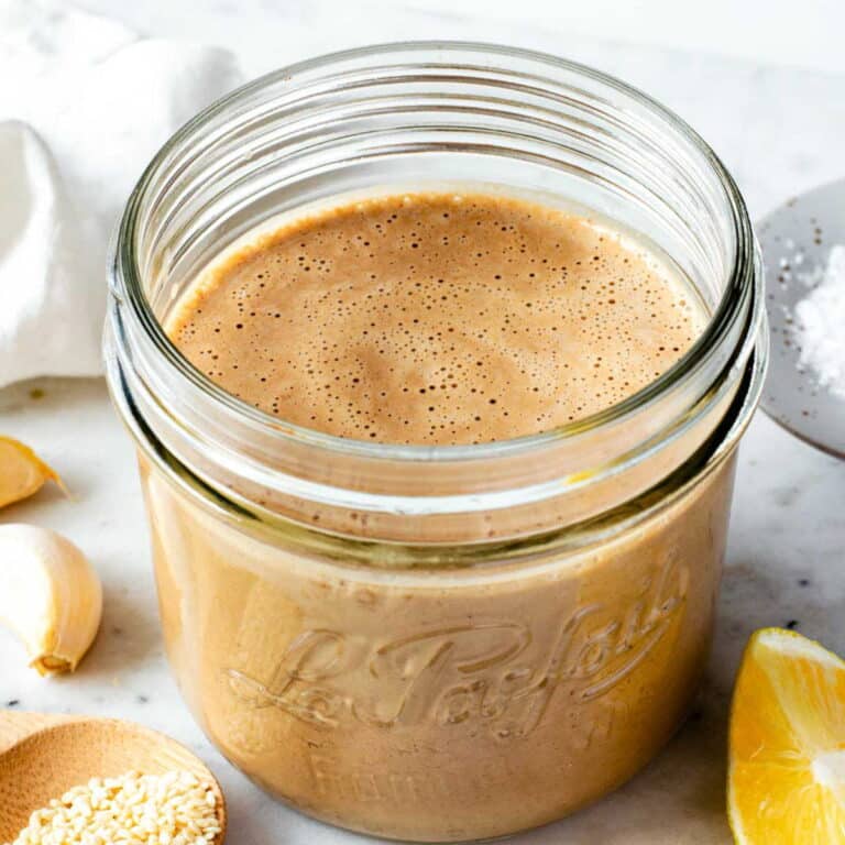 Tahini balsamic dressing in a small mason jar placed over a marble board.