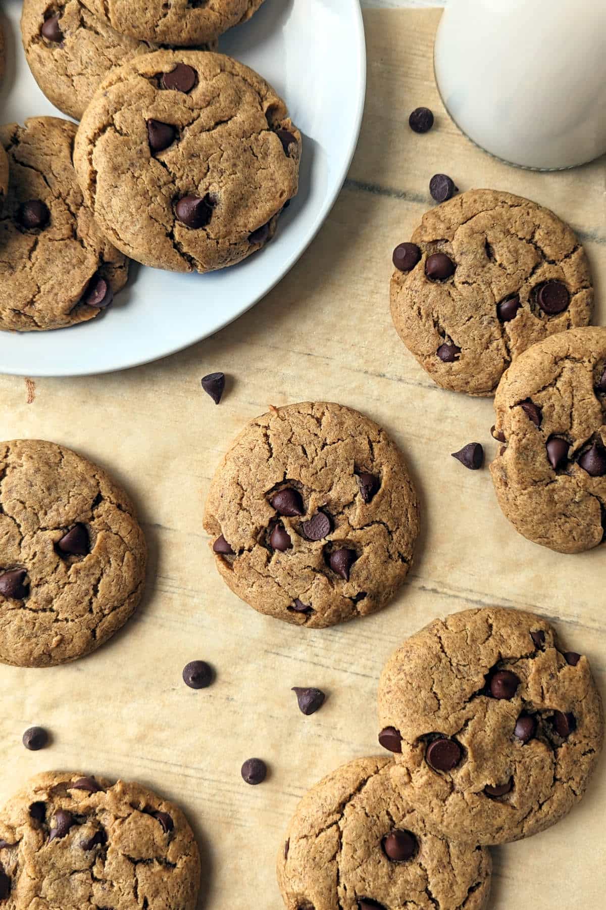 Several cookies on parchment paper with chocolate chips scattered around.