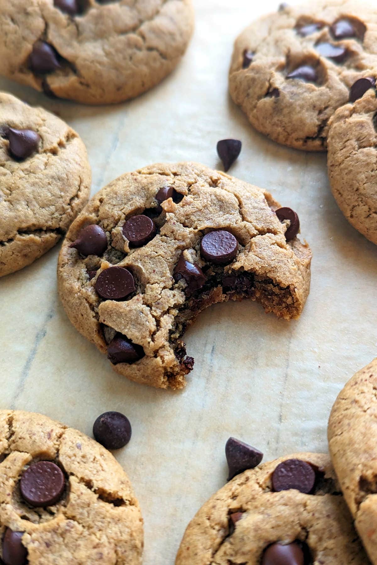A vegan peanut butter chocolate chip cookie with a bite taken out of it.