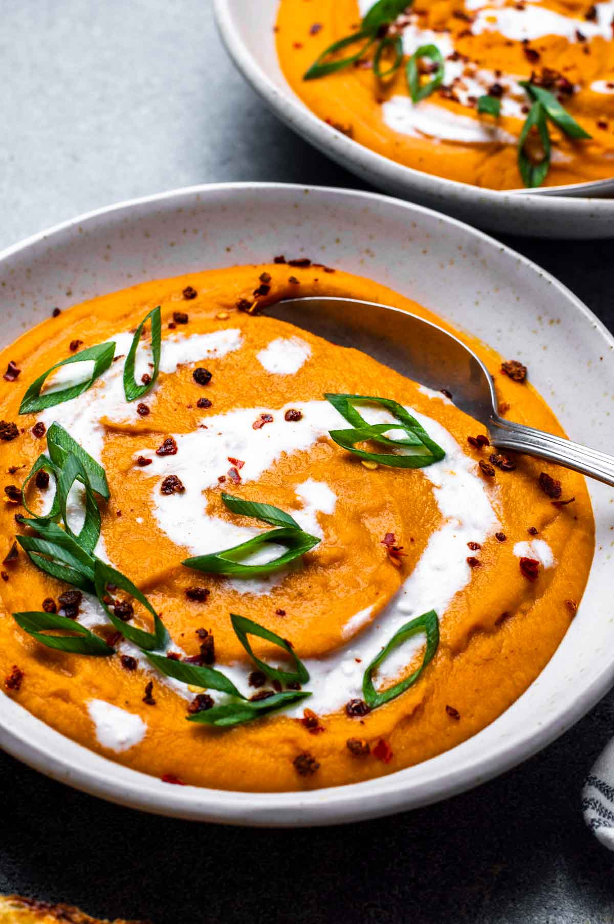 Carrot lentil soup in a serving bowl, ready with a spoon.