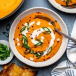 Carrot lentil soup in a serving bowl, ready with a spoon.