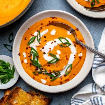 Carrot lentil soup in a serving bowl, ready with a spoon.