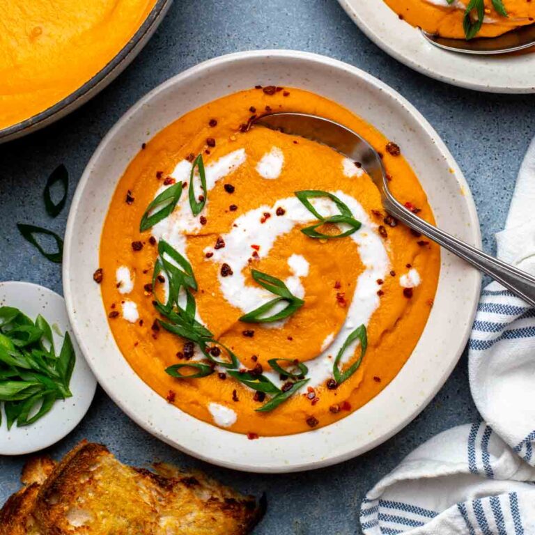 Carrot lentil soup in a serving bowl, ready with a spoon.