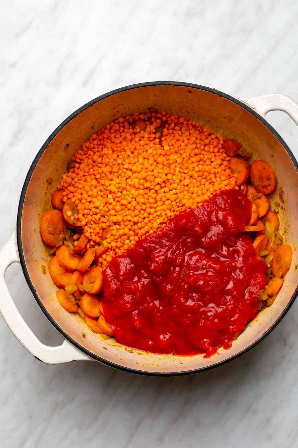 Carrots, lentils, and crushed tomatoes added to a large stockpot.
