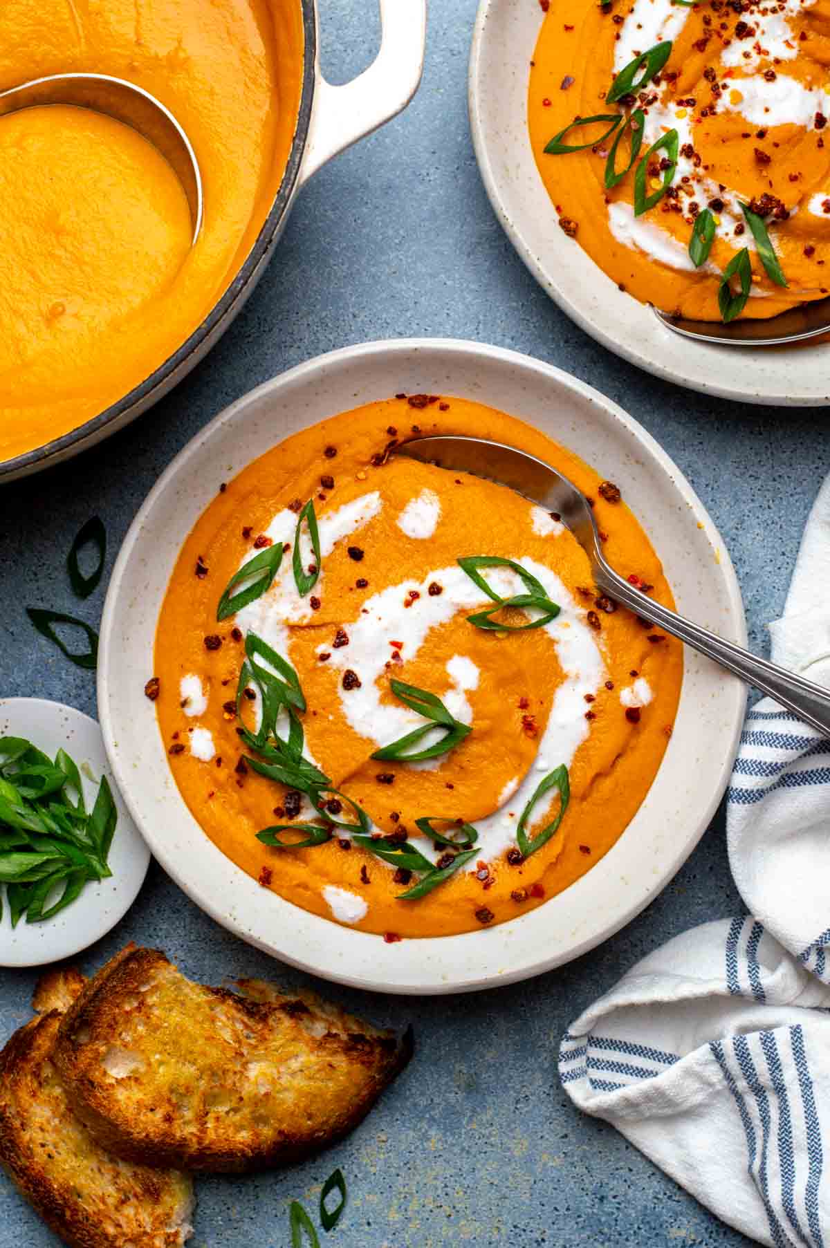 Carrot lentil soup in a serving bowl, ready with a spoon.