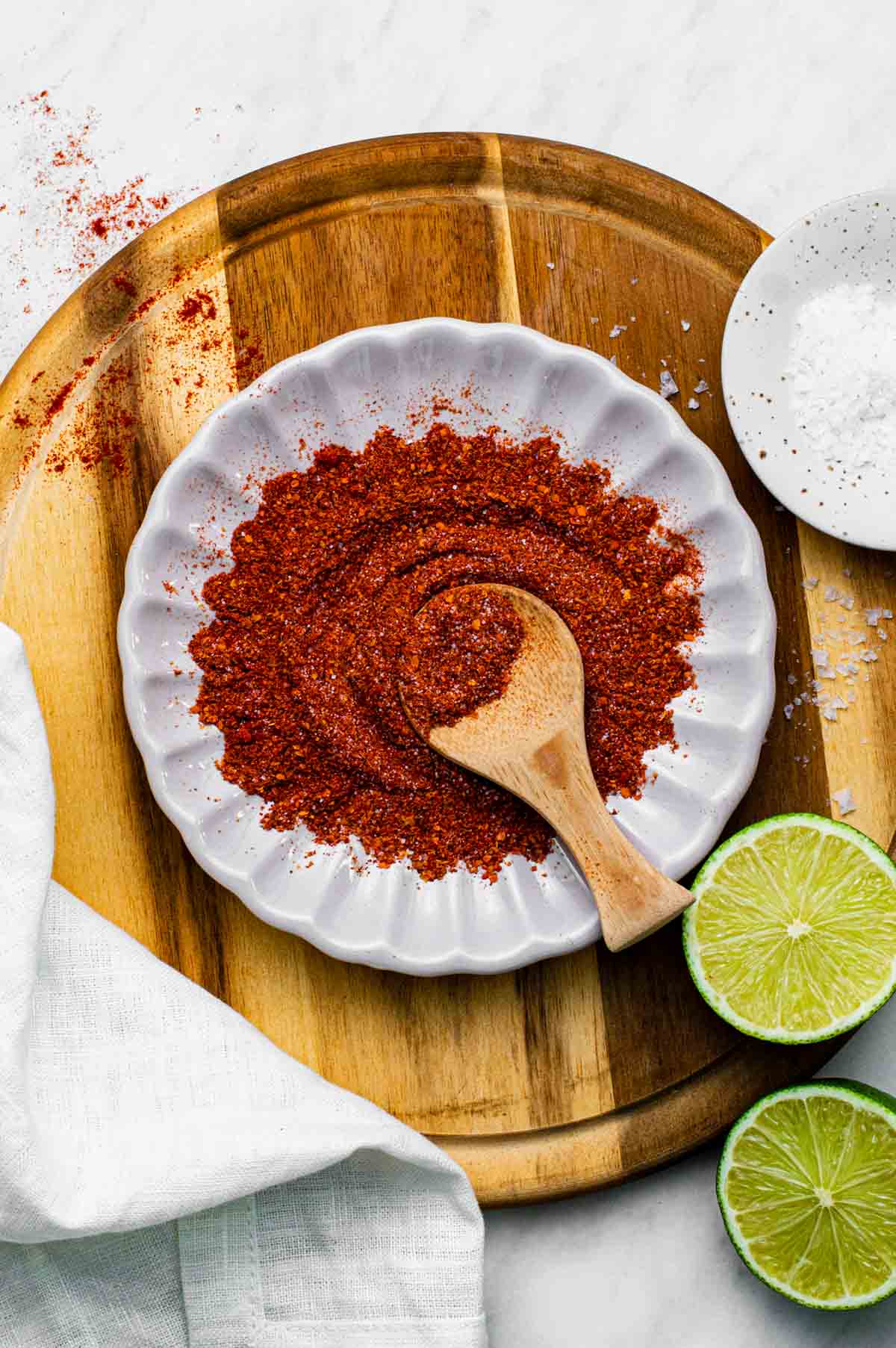 Chili lime seasoning on a small white plate with a wooden scoop.
