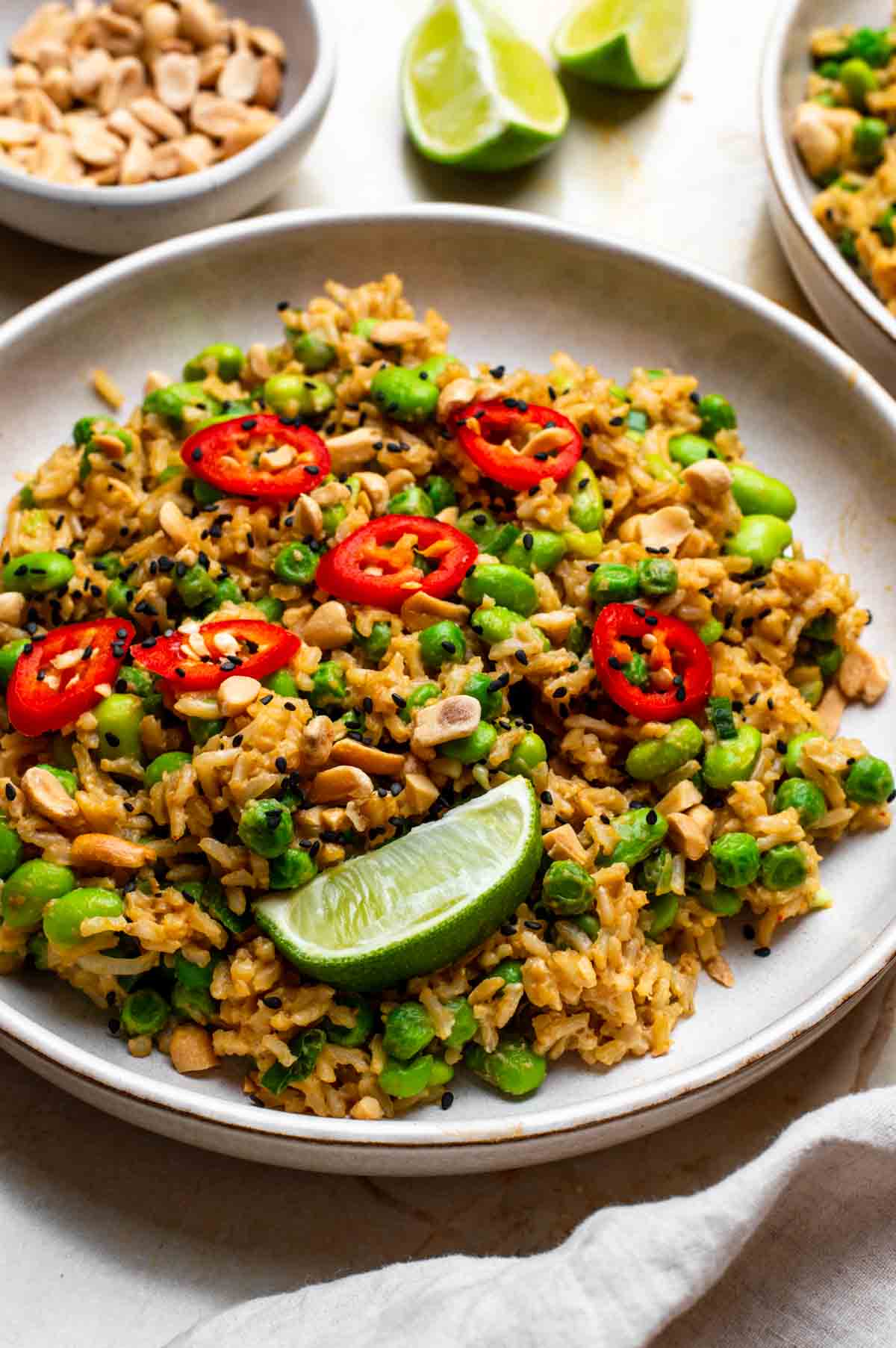 Peanut butter rice on a plate with chili on top and lime on the side.