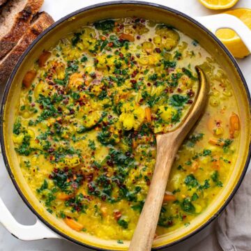 A bowl of cauliflower lentil soup with a wooden spoon resting inside.