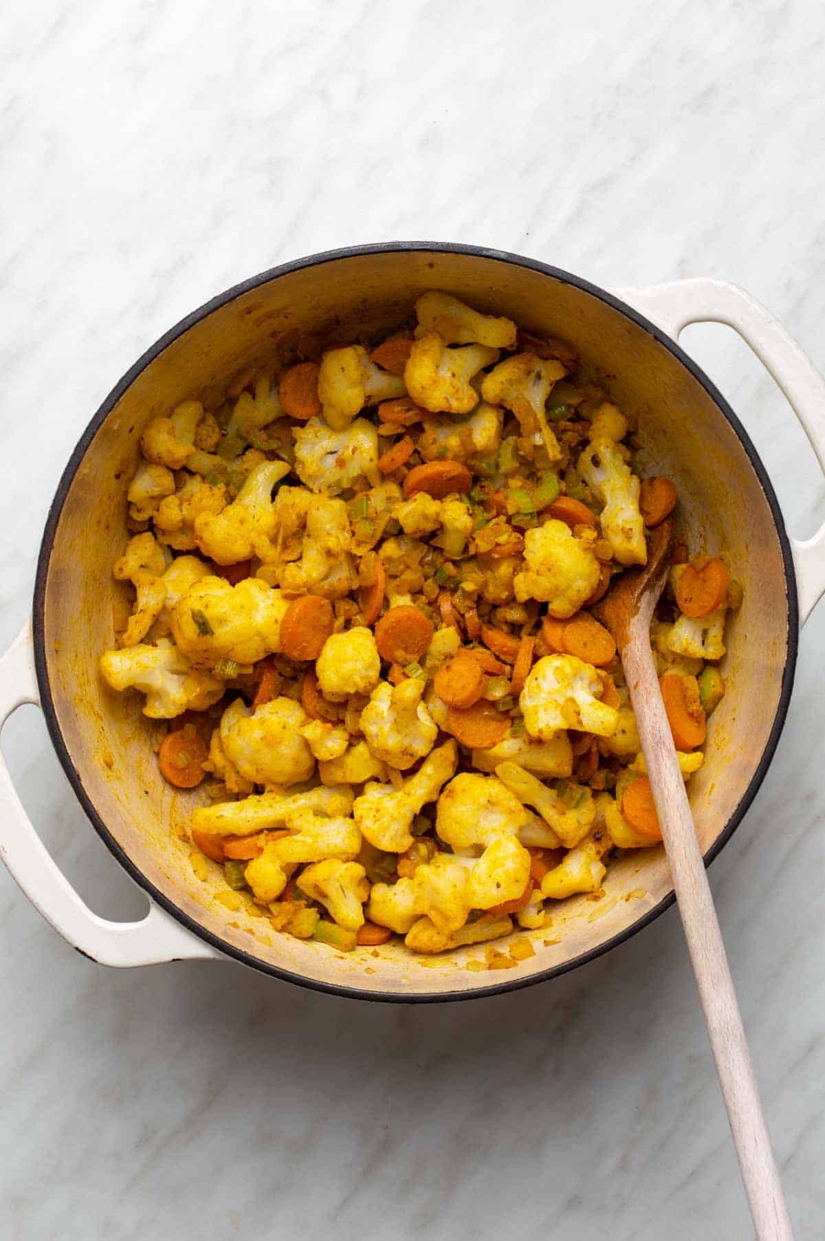 A mix of chopped vegetables, lentils, and seasonings prepared for making cauliflower lentil soup.