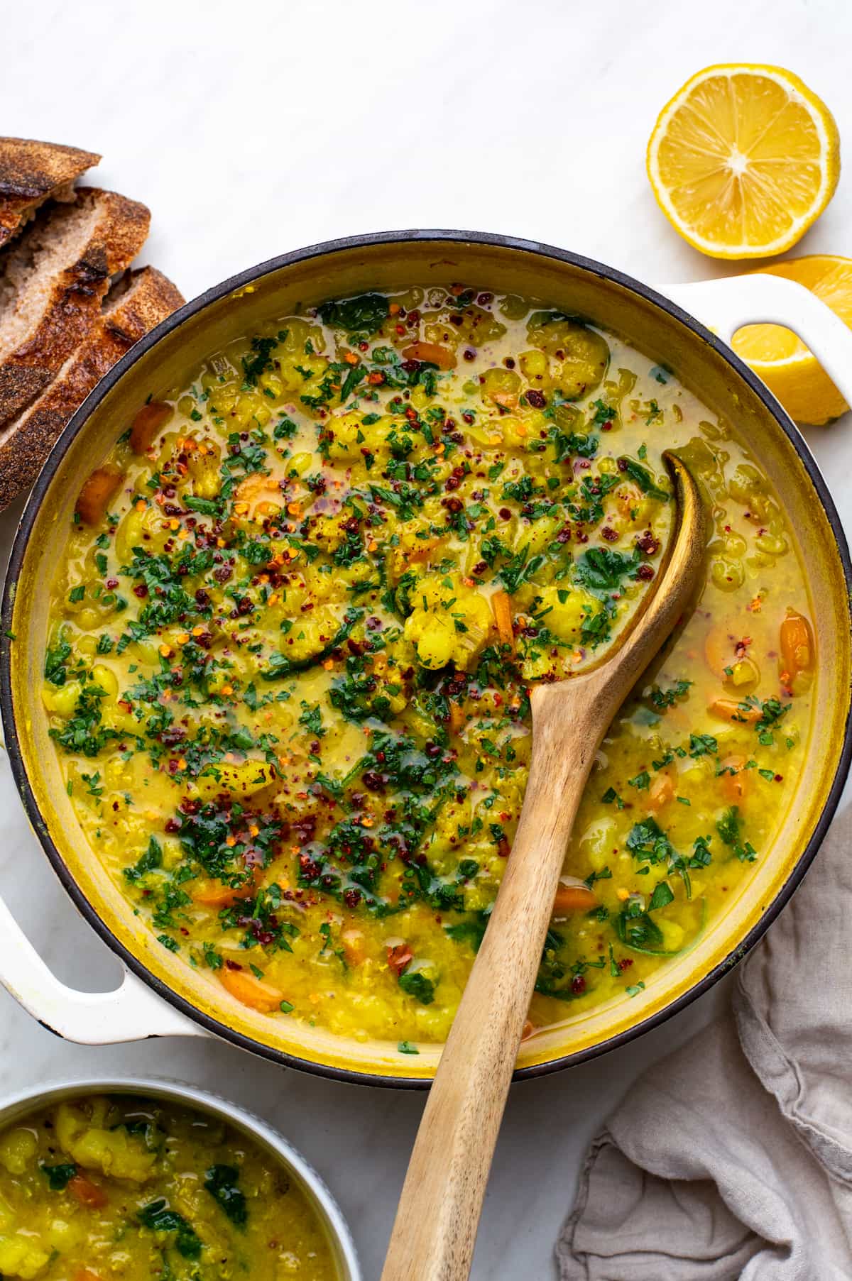 A bowl of cauliflower lentil soup with a wooden spoon resting inside.