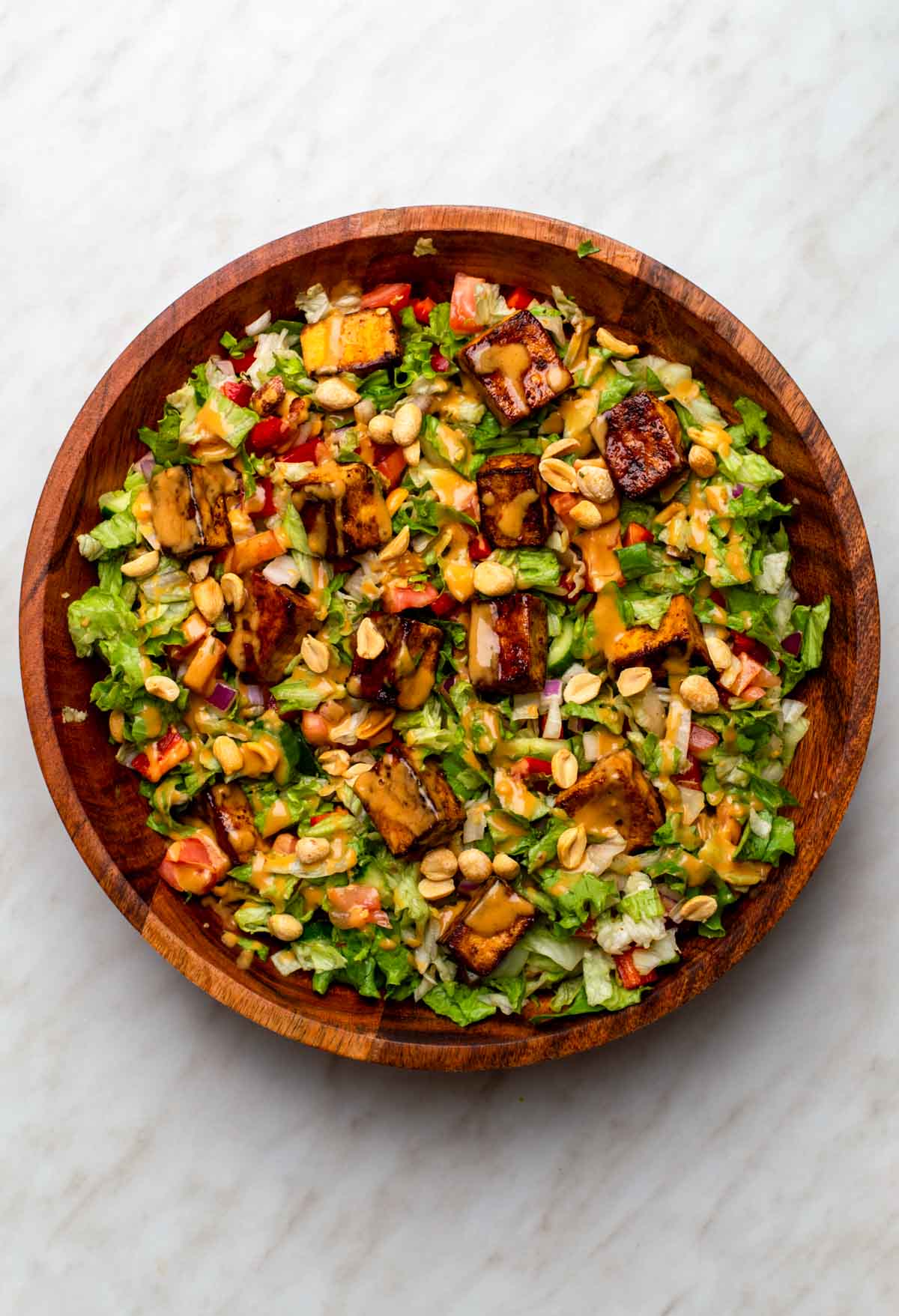 A bowl of Thai tofu salad with colorful vegetables, crispy tofu cubes, and fresh herbs.