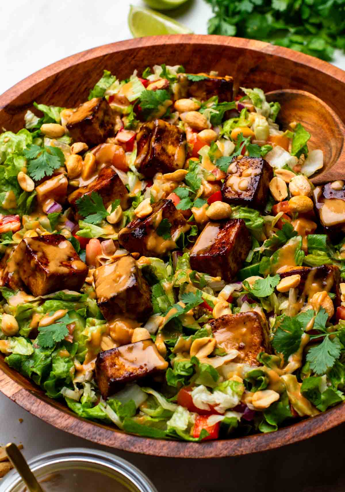 A bowl of Thai tofu salad with colorful vegetables, crispy tofu cubes, and fresh herbs.