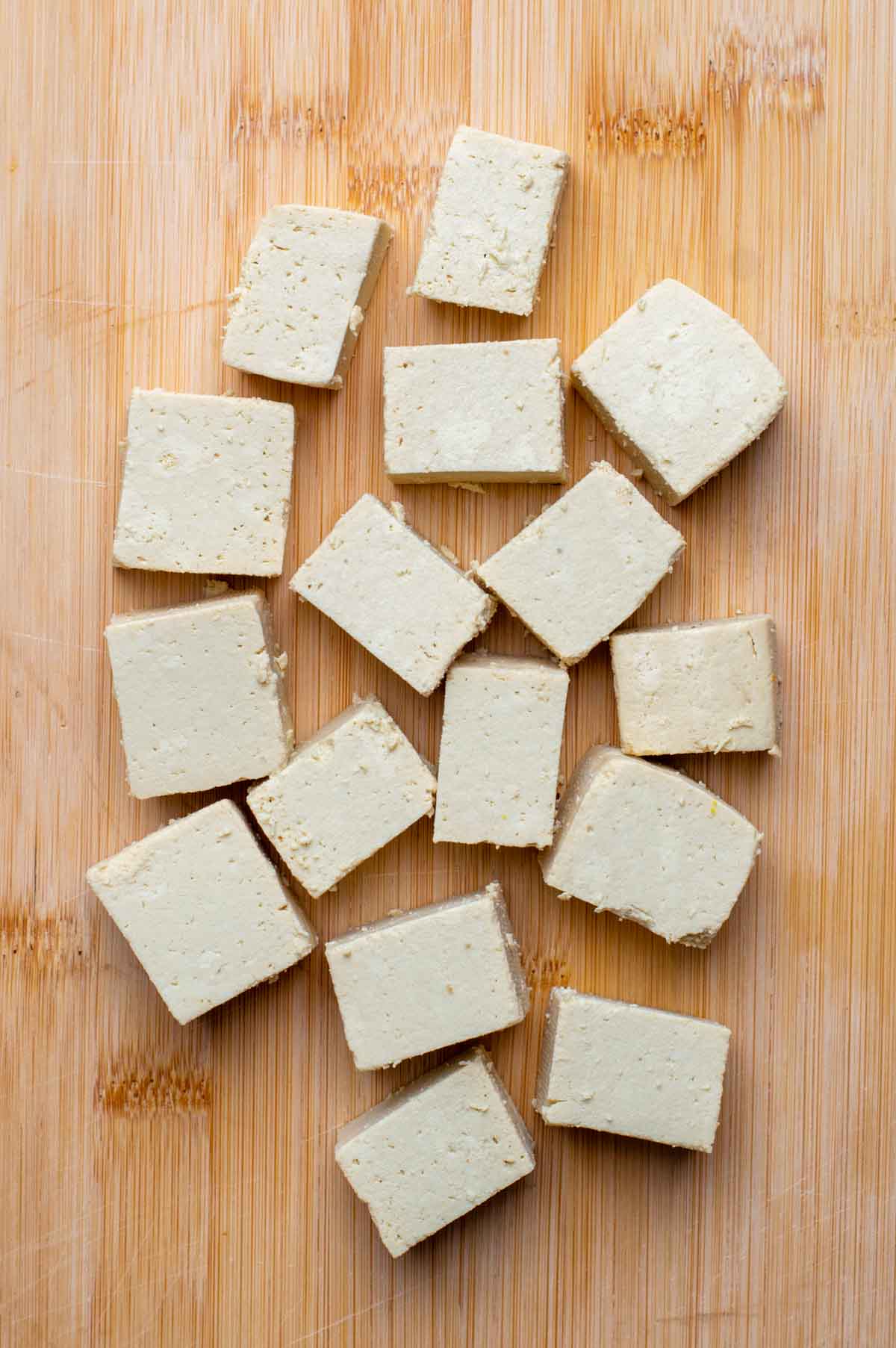 Cubed pieces of tofu neatly arranged on a cutting board.