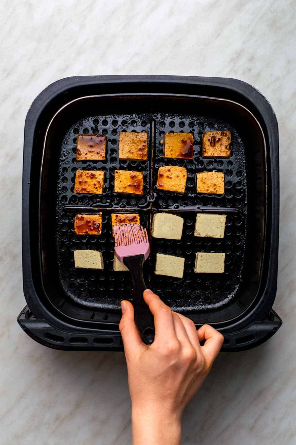 A baking pan filled with marinated tofu cubes, ready for the oven.