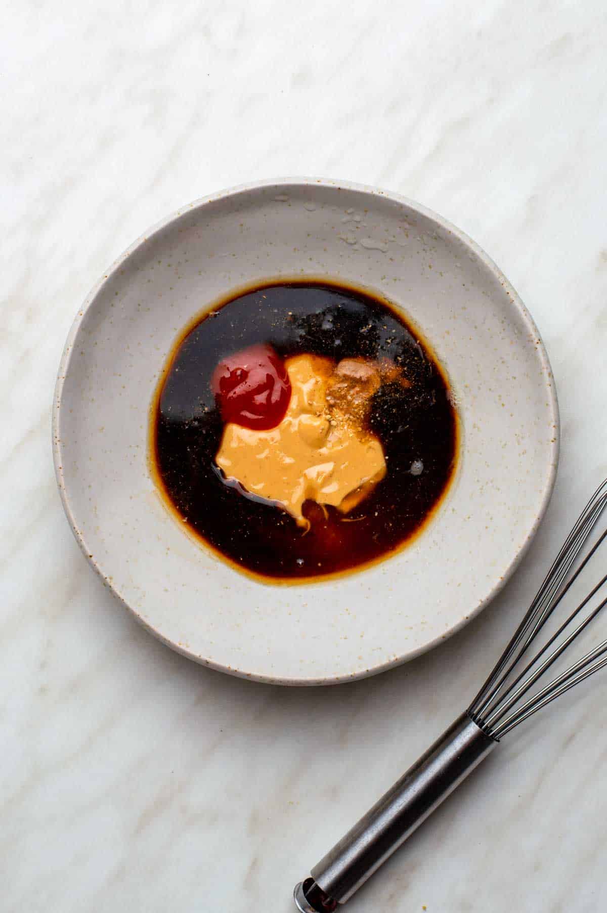 A bowl containing a mix of dressing ingredients, ready to be whisked together.