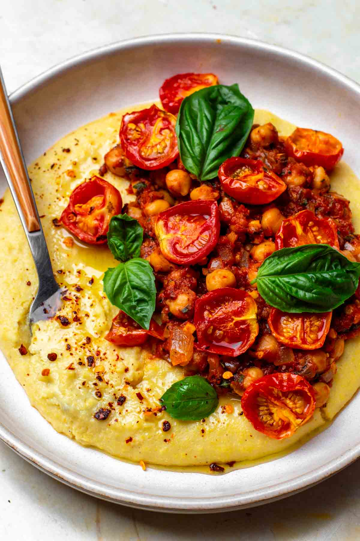 Creamy vegan polenta served on a plate with a spoon.