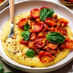 Creamy vegan polenta served on a plate with a spoon.