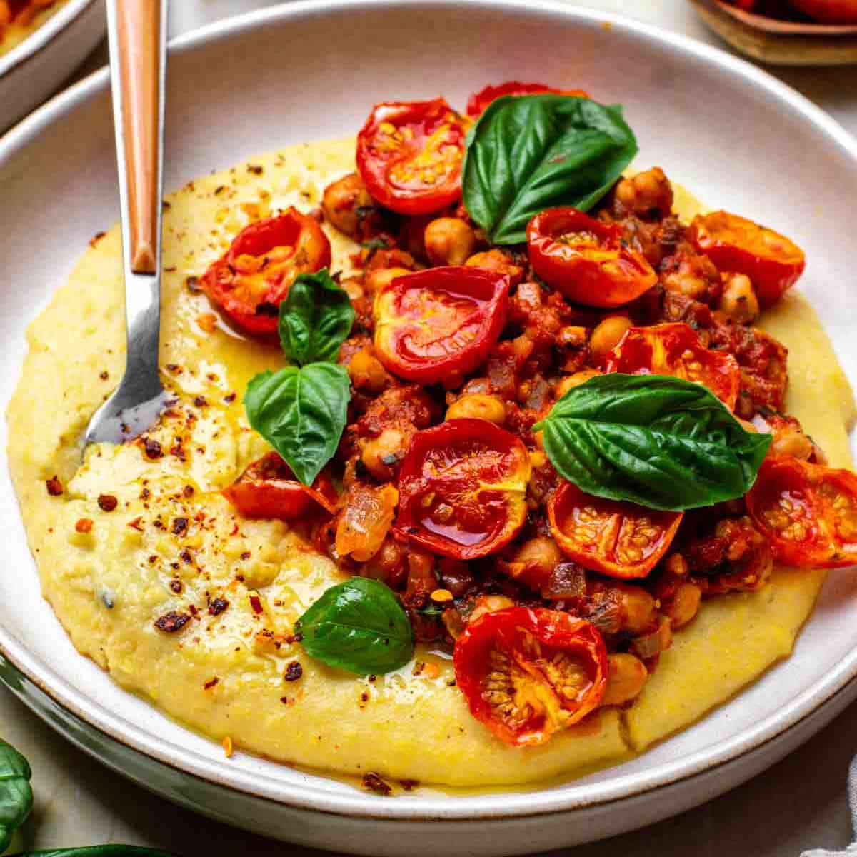 Creamy vegan polenta served on a plate with a spoon.