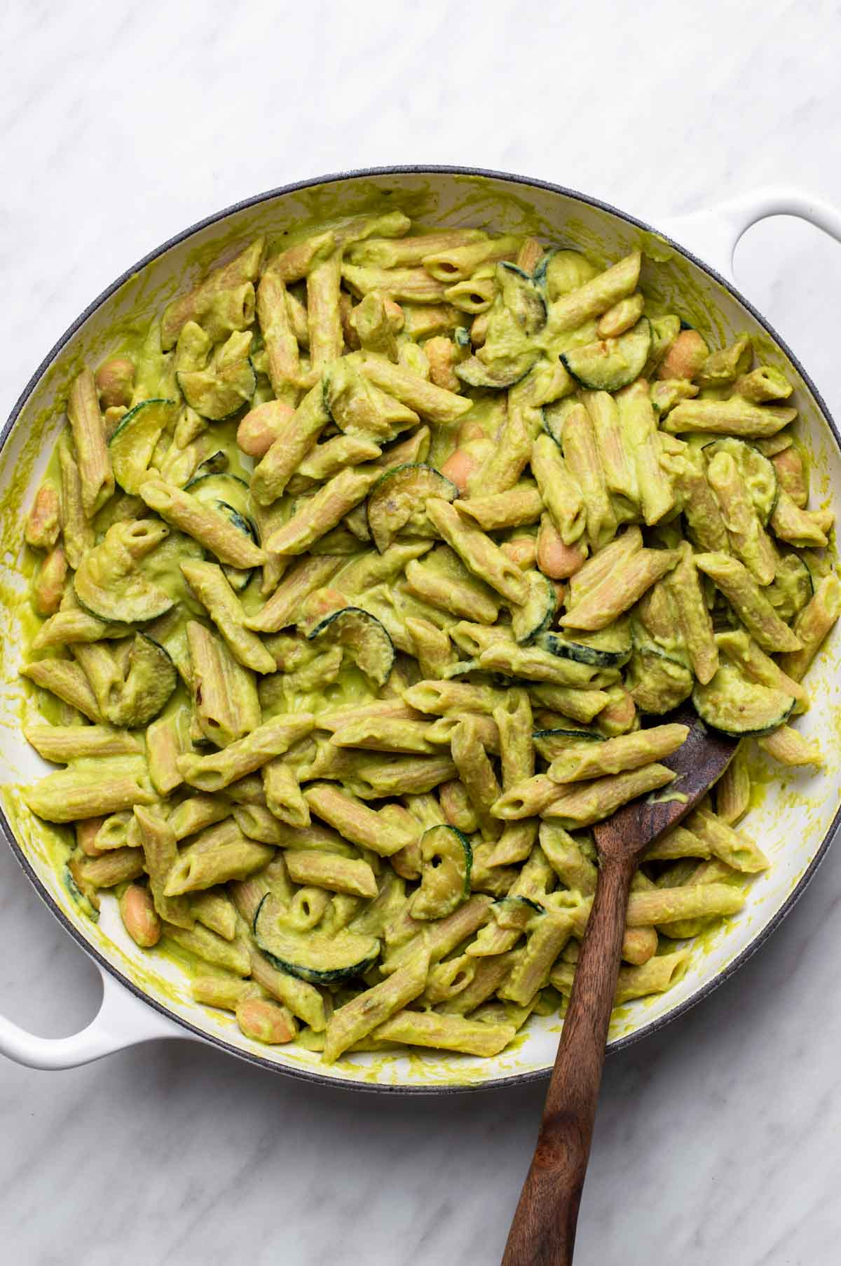 Pasta mixed together with creamy zucchini sauce in a pan.