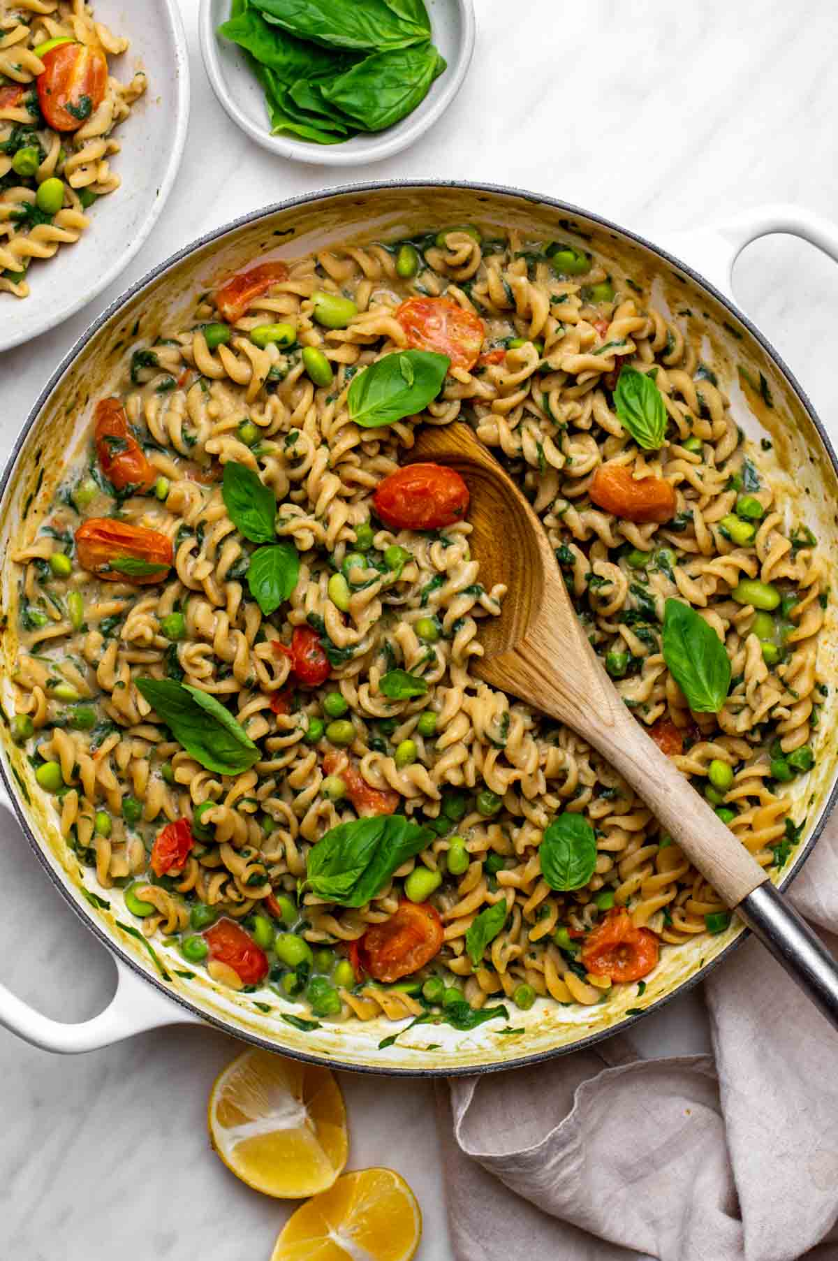 A pan filled with creamy veggie pasta mixed with colorful vegetables.