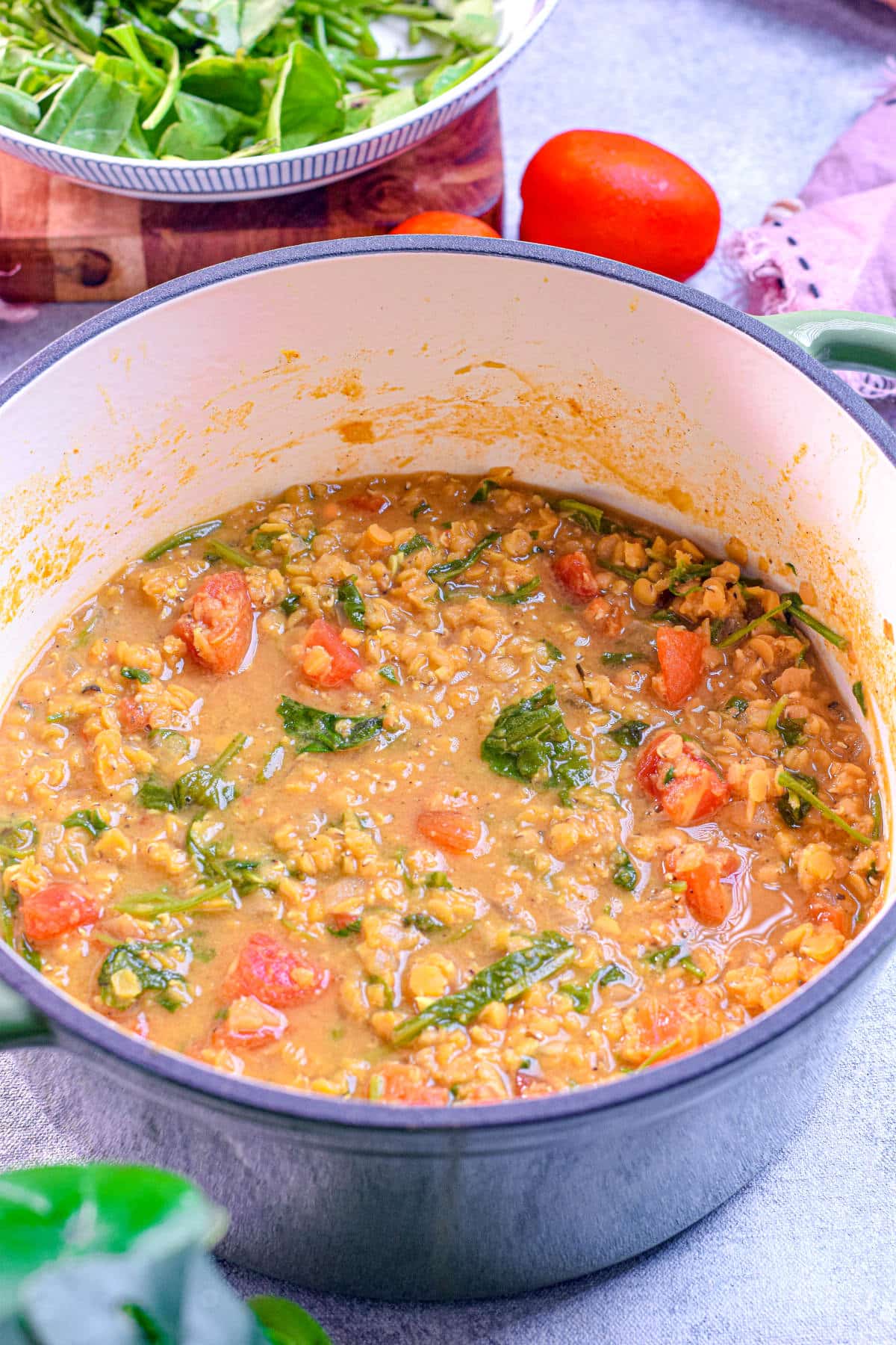 A bowl of hearty red lentil and spinach soup with a rich, golden-orange color.