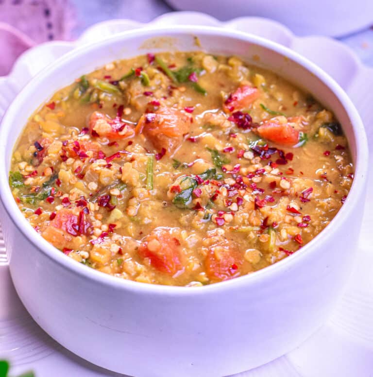 A bowl of hearty red lentil and spinach soup with a rich, golden-orange color.
